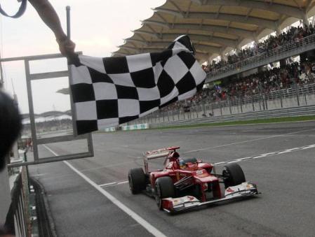 Fernando Alonso pasa bajo la bandera a cuadros en Sepang 2012.